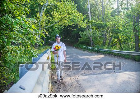 Man on roadside holding flowers View Large Photo Image Stock Image - Man on roadside holding flowers. Fotosearch