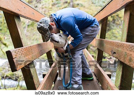 Man on wooden footbridge kissing dog View Large Photo Image Stock Image - Man on wooden footbridge kissing dog. Fotosearch