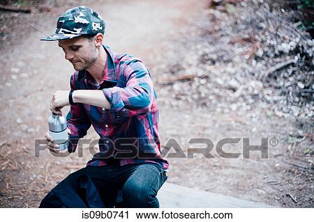 Stock Image - Man opening bottled water, Big Sur, California, USA. Fotosearch