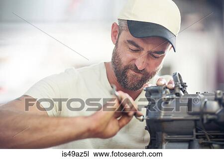 Man repairing outboard motor in boat repair workshop View Large Photo Image Stock Image - Man repairing outboard motor in boat repair workshop. Fotosearch
