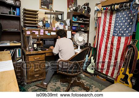 Man sitting at desk using laptop View Large Photo Image Stock Photograph - Man sitting at desk using laptop. Fotosearch