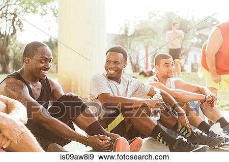 Man sitting with friends tying shoelace smiling View Large Photo Image Stock Photo - Man sitting with friends tying shoelace smiling. Fotosearch
