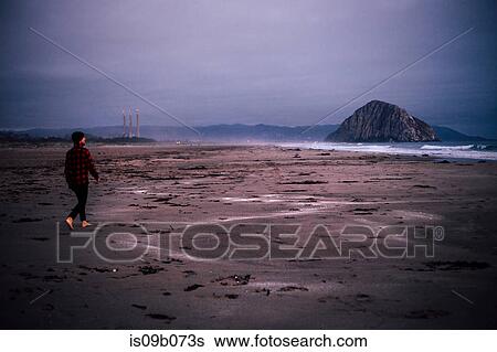 Stock Photograph - Man walking barefoot on overcast beach, Morro Bay, California, USA. Fotosearch