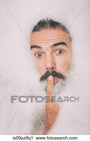Stock Image - Man with moustache covered in bubbles finger on lips. Fotosearch