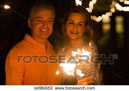 Mature adult couple playing with sparkler in garden at night View Large Photo Image Stock Image - Mature adult couple playing with sparkler in garden at night. Fotosearch