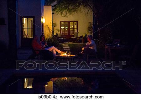 Mature adults relaxing by patio fire at dusk View Large Photo Image Stock Photo - Mature adults relaxing by patio fire at dusk. Fotosearch