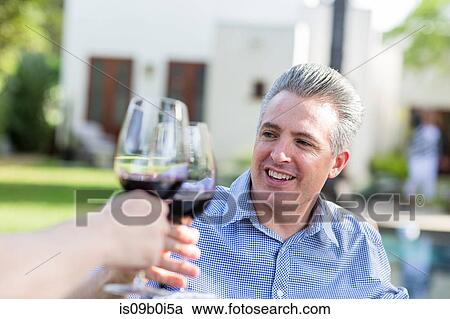 Mature couple making a red wine toast in garden View Large Photo Image Stock Image - Mature couple making a red wine toast in garden. Fotosearch