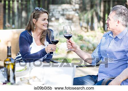 Mature couple making a red wine toast at garden table View Large Photo Image Stock Image - Mature couple making a red wine toast at garden table. Fotosearch