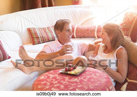 Mature couple relaxing at home, holding drink, eating strawberries View Large Photo Image Stock Photo - Mature couple relaxing at home, holding drink, eating strawberries. Fotosearch