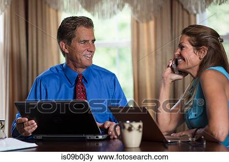 Mature couple sitting at home, using laptops View Large Photo Image Stock Photo - Mature couple sitting at home, using laptops. Fotosearch