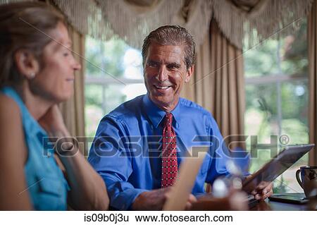 Stock Photograph - Mature couple sitting at home, using laptops. Fotosearch