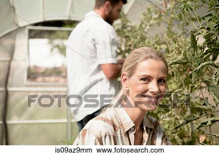 Mature couple tending to plants in greenhouse View Large Photo Image Picture - Mature couple tending to plants in greenhouse. Fotosearch