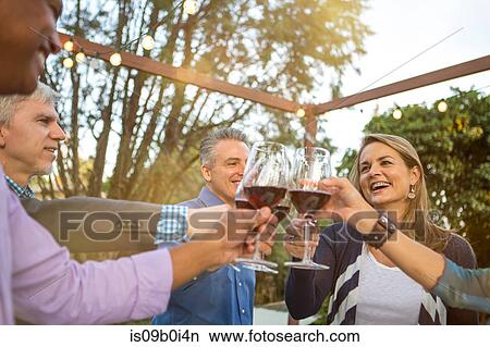 Mature friends in a circle making a red wine toast at garden party View Large Photo Image Picture - Mature friends in a circle making a red wine toast at garden party. Fotosearch