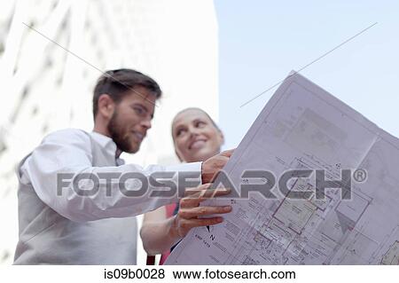 Mature man and woman outdoors, holding blueprints, low angle view View Large Photo Image Stock Photo - Mature man and woman outdoors, holding blueprints, low angle view. Fotosearch