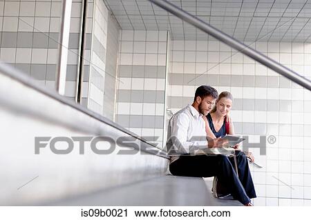 Mature man and woman sitting on steps, looking at digital tablet View Large Photo Image Stock Image - Mature man and woman sitting on steps, looking at digital tablet. Fotosearch