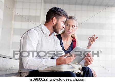 Mature man and woman sitting on steps, looking at digital tablet View Large Photo Image Stock Image - Mature man and woman sitting on steps, looking at digital tablet. Fotosearch