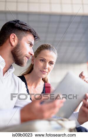 Mature man and woman sitting outdoors, looking at digital tablet View Large Photo Image Stock Image - Mature man and woman sitting outdoors, looking at digital tablet. Fotosearch