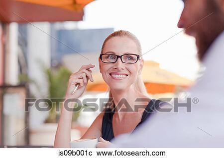 Stock Image - Mature man and woman, sitting outside cafe, having discussion. Fotosearch