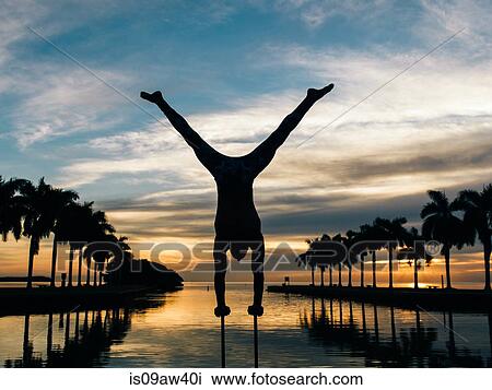 Stock Image - Mature man balancing on poles, dusk, South Pointe Park, South Beach, Miami, Florida, USA. Fotosearch