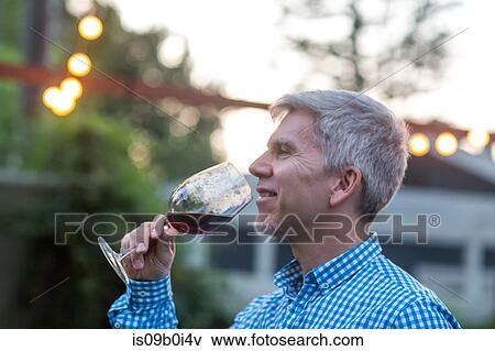 Mature man drinking red wine at garden party at dusk View Large Photo Image Stock Photo - Mature man drinking red wine at garden party at dusk. Fotosearch