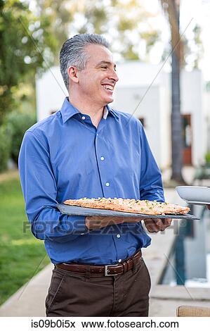 Mature man holding fish cuisine on cutting board at garden party View Large Photo Image Stock Photo - Mature man holding fish cuisine on cutting board at garden party. Fotosearch