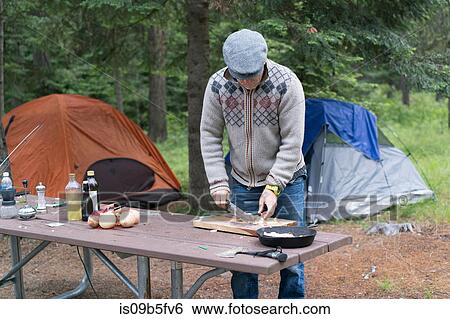 Stock Photograph - Mature man preparing food on campsite, Washington, USA. Fotosearch