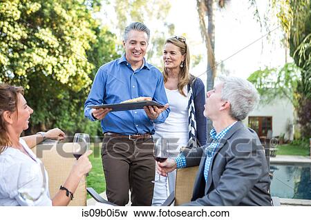 Mature man serving fish cuisine at garden party View Large Photo Image Stock Photo - Mature man serving fish cuisine at garden party. Fotosearch