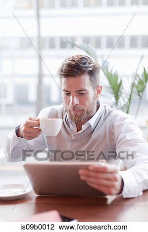Mature man sitting in cafe, drinking coffee, using digital tablet View Large Photo Image Stock Image - Mature man sitting in cafe, drinking coffee, using digital tablet. Fotosearch