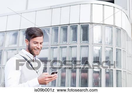 Stock Photo - Mature man walking outdoors, using smartphone. Fotosearch