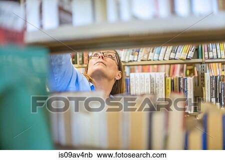 Mature woman behind book shelves in library View Large Photo Image Stock Image - Mature woman behind book shelves in library. Fotosearch