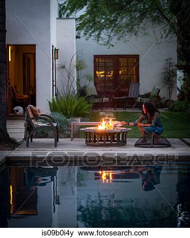 Mature woman burning newspaper on patio fire at dusk View Large Photo Image Stock Photo - Mature woman burning newspaper on patio fire at dusk. Fotosearch