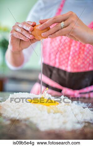 Mature woman cracking egg onto flour, mid section View Large Photo Image Stock Image - Mature woman cracking egg onto flour, mid section. Fotosearch