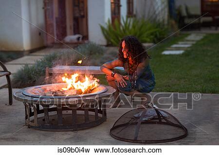 Mature woman crouching in front of patio fire at dusk View Large Photo Image Stock Photo - Mature woman crouching in front of patio fire at dusk. Fotosearch