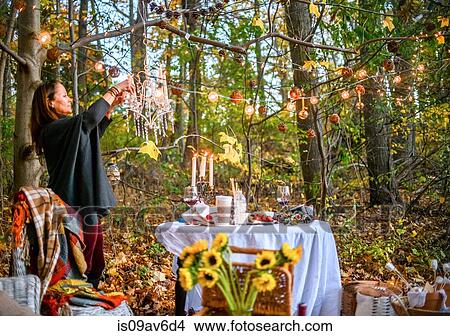 Mature woman hanging decorative lights in woods View Large Photo Image Picture - Mature woman hanging decorative lights in woods. Fotosearch