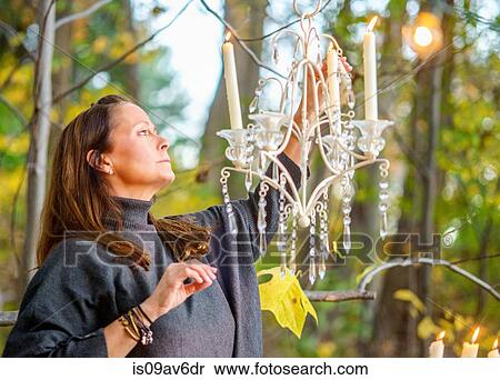 Mature woman lighting chandelier candle in woods View Large Photo Image Stock Photography - Mature woman lighting chandelier candle in woods. Fotosearch