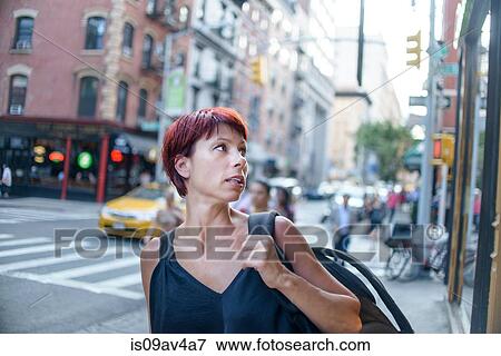 Stock Photo - Mature woman looking over her shoulder on city street. Fotosearch