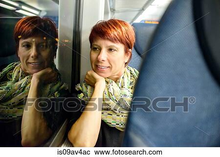 Mature woman looking through window whilst sitting on train at night View Large Photo Image Stock Image - Mature woman looking through window whilst sitting on train at night. Fotosearch