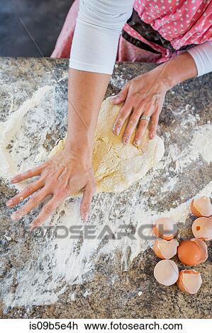 Stock Image - Mature woman making home made pasta, overhead view. Fotosearch