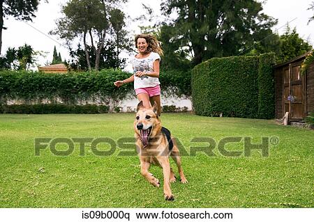 Stock Photography - Mature woman running in park with dog. Fotosearch