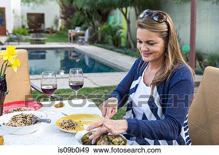 Mature woman serving food at garden table View Large Photo Image Stock Photo - Mature woman serving food at garden table. Fotosearch