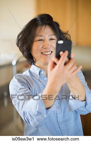Mature woman taking selfie indoors View Large Photo Image Stock Image - Mature woman taking selfie indoors. Fotosearch