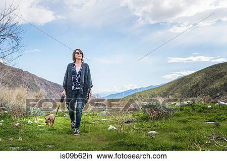 Mature woman walking dog in valley landscape View Large Photo Image Picture - Mature woman walking dog in valley landscape. Fotosearch