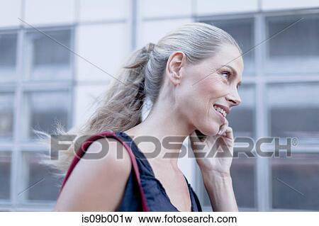 Mature woman, walking outdoors, using smartphone View Large Photo Image Stock Photo - Mature woman, walking outdoors, using smartphone. Fotosearch