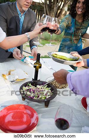 Stock Photograph - Mature women making wine toast at garden party table. Fotosearch