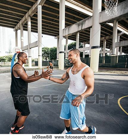 Stock Photo - Men on basketball court shaking hand smiling. Fotosearch