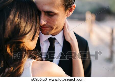 Stock Image - Mid adult couple outdoors, in romantic embrace. Fotosearch
