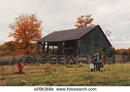 Stock Image - Mid adult family with three daughters strolling in rural field. Fotosearch