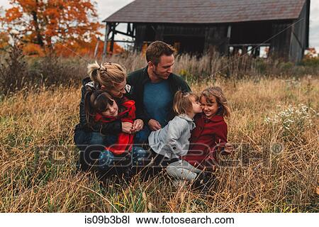 Stock Image - Mid adult family with three daughters together in rural field. Fotosearch