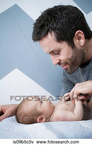 Mid adult man and baby son gazing at each other on bed View Large Photo Image Stock Photo - Mid adult man and baby son gazing at each other on bed. Fotosearch