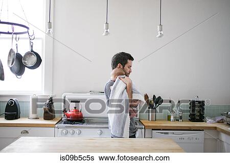 Mid adult man carrying baby son in kitchen View Large Photo Image Stock Photograph - Mid adult man carrying baby son in kitchen. Fotosearch